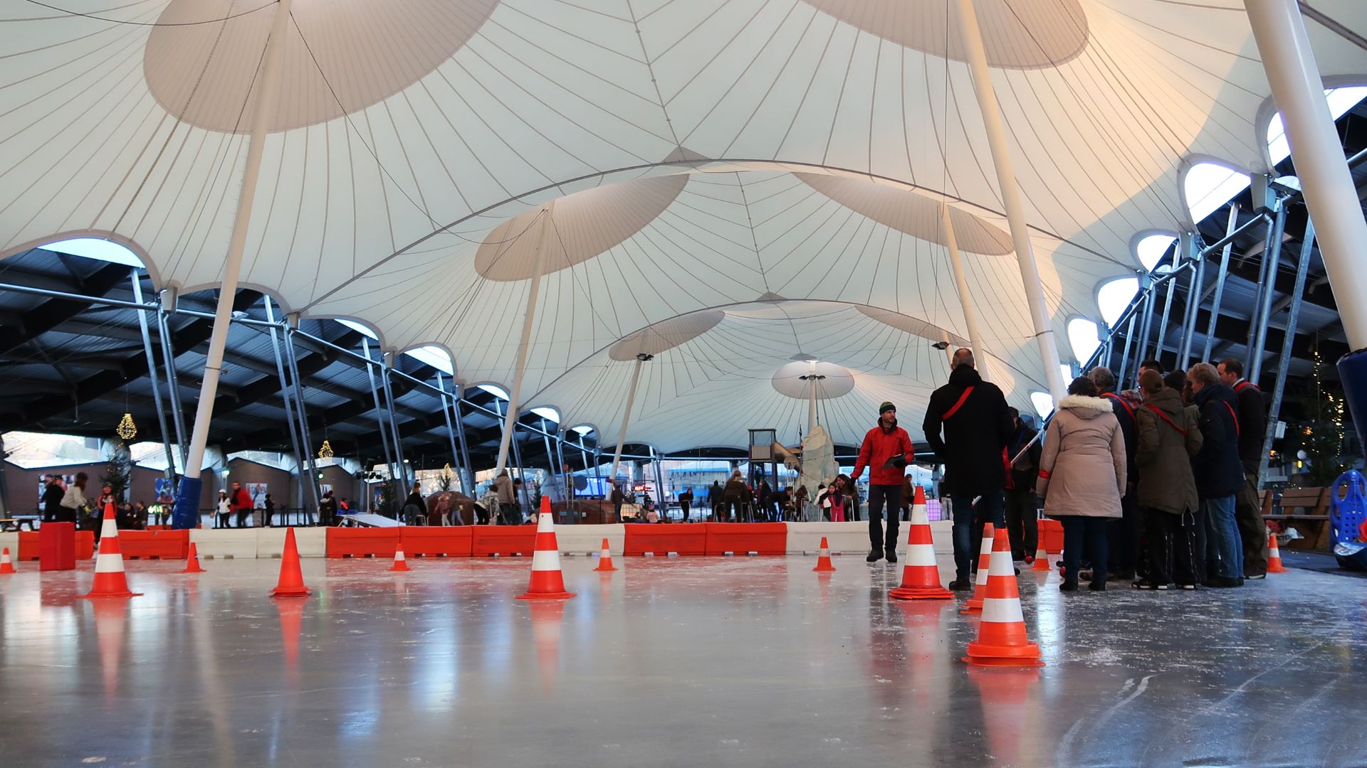 Archieffoto van de overdekte ijsbaan De Scheg in Deventer met schaatsers en oranje pionnen op het ijs.