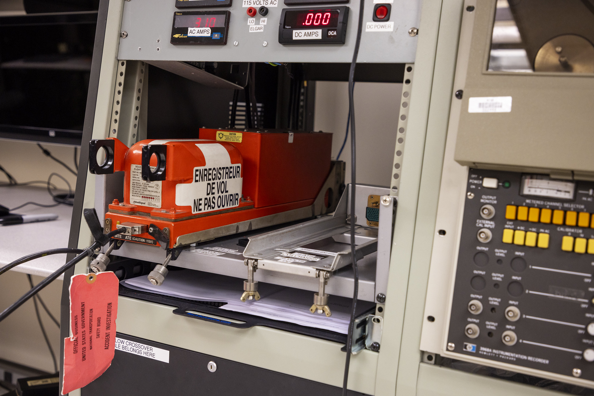 De oranje vluchtrecorder van vlucht 7598 tussen testapparatuur in het NTSB-laboratorium.