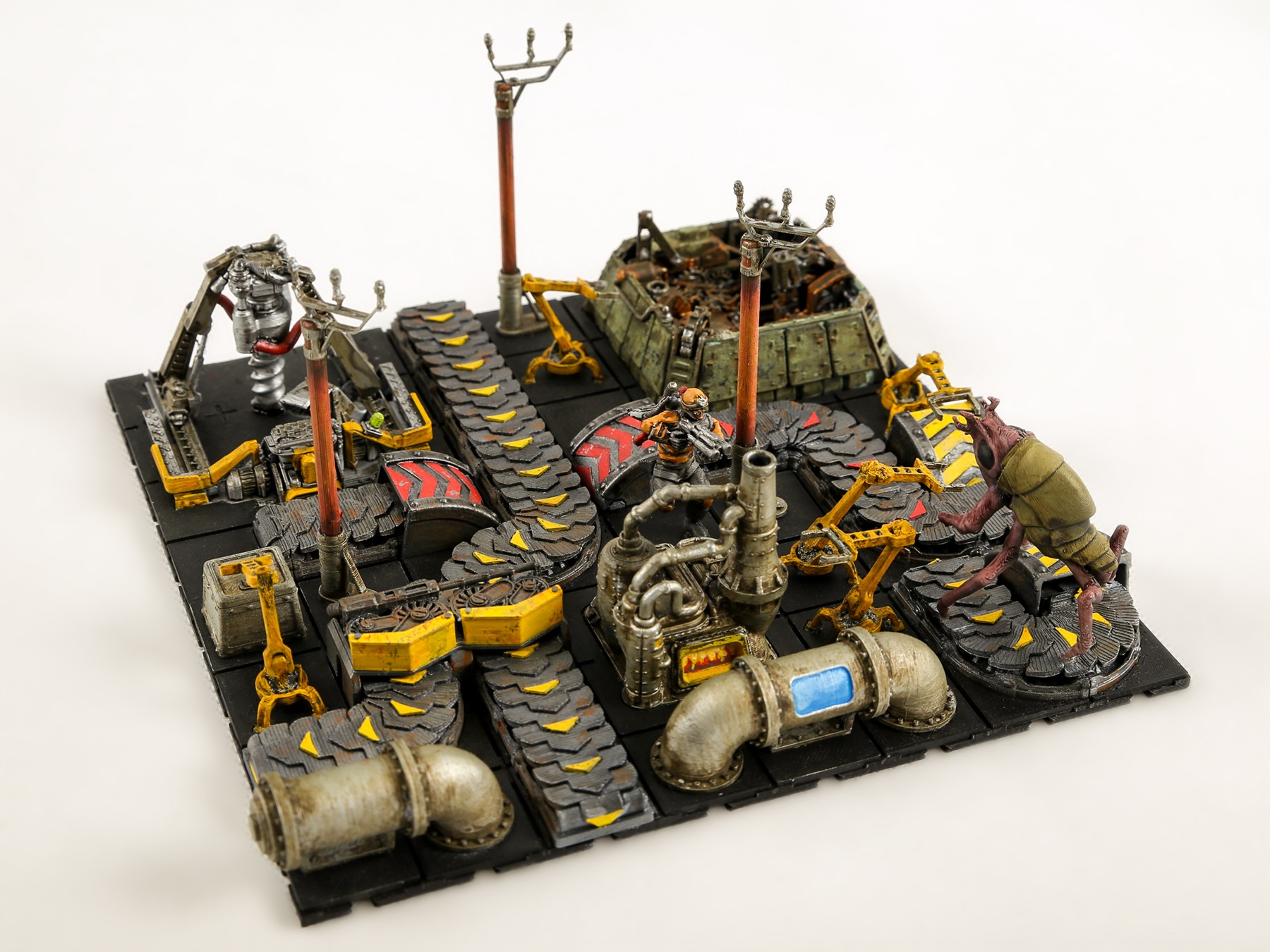 Foto van Wube Software: een Factorio-miniatuurfabriek met transportbanden, grijparmen, machines en een groot insectachtig wezen.